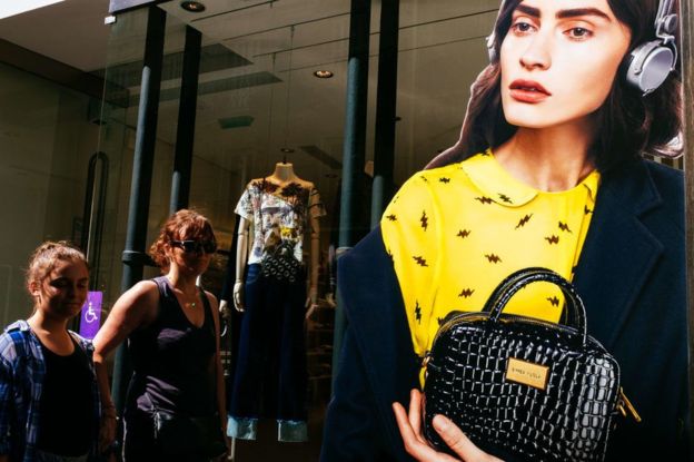 Mulheres passam em frente a uma vitrine em Paris